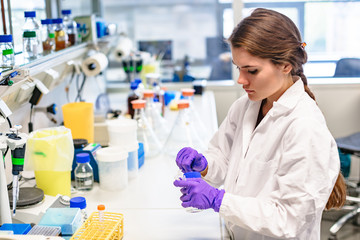 Woman researcher puts flask with sample into box