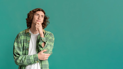 Dreamy handsome guy thinking on turquoise background, space for text. Panorama