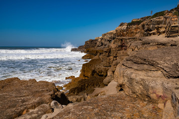 Fototapeta na wymiar Rocky coastline on the beach - Praia do Magoito at the Atlantic Ocean near Sintra, Portugal.