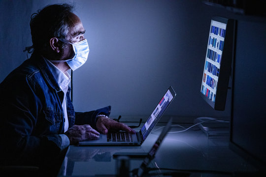 Impegato lavora al suo compuetr con la mascherina