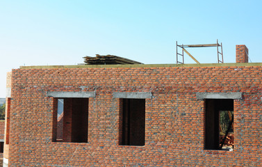 Incomplete brick house construction with window openings and without roof.