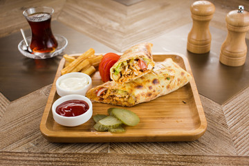 Shawarma pita bread with grilled chicken, shaurma doner, fresh vegetables and cream sauce on a light stone or concrete background. Top view with copy space, concept restaurant fast food