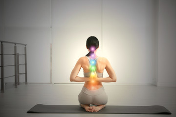 Young woman with chakra points practicing yoga in studio, back view. Healing energy - obrazy, fototapety, plakaty