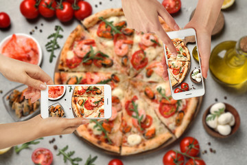 Food bloggers taking pictures of delicious seafood pizza at light grey table, closeup