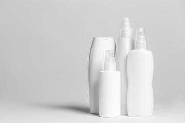 Set of cosmetic products in white and grey containers on light background.
