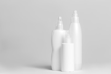 Set of cosmetic products in white and grey containers on light background.