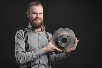 Handsome young man presents car parts on a gray background. The concept of sales and testing of goods