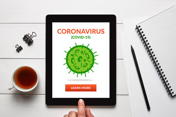 Coronavirus, covid-19 concept on tablet screen with office objects on white wooden table. Social distancing. Top view