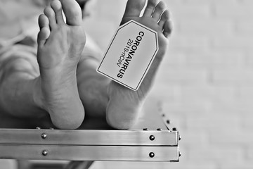 concept imitation morgue, coronavirus victim killed by 2019-ncov, legs of a corpse on a table, man...