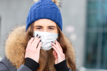 Portrait of woman walking down the street in winter in a protective mask to protect against infectious diseases. Protection against colds, flu, air pollution. Health concept