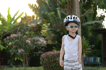 cute child wear sunglasses and sport helmet playing bicycle exercise in the morning day