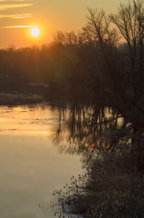 In the spring dawn, the red sun rises over the river.