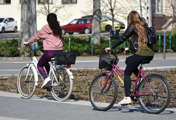 Naklejka na ściany i meble Young women with bicycles on the city street