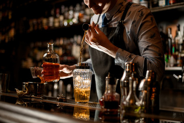 bartender using beaker carefully pours drink into glass shaker