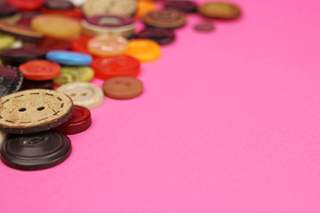 Obraz na płótnie Canvas Sewing buttons of various sizes , shapes and colors on a pink background, copy space
