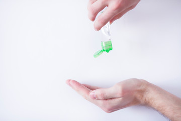 Man's hands on the white background. Using a disinfectant gel against novel coronavirus (2019-nCoV) at home. Home isolation. Antiseptic, Hygiene and Healthcare concept. Space for a text.