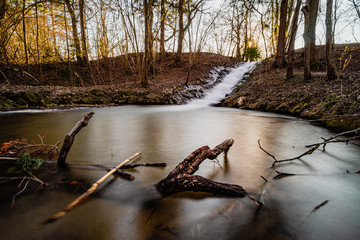Sonnenuntergang mit oranger Sternensonne über Wasserfall Teich im Wald (Wiesbach bei Landsberg a....
