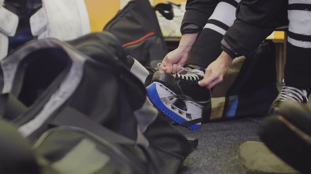 Lockdown of unrecognizable hockey player lacing up skates in cloakroom
