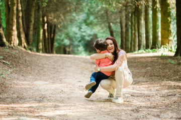 Mother having fun with cute son in summer park. Happy woman with cheerful little boy outdoors