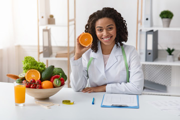 Modern dietologist african woman recommending fresh oranges - Powered by Adobe