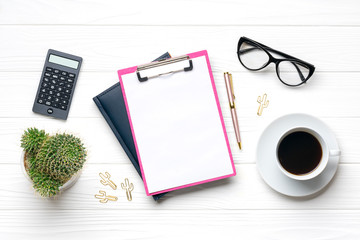 Fashion feminine home office workplace. Tablet, calculator, notepad, golden pen, clips, glasses, cup of coffee, succulent on white wooden background Top view Flat lay