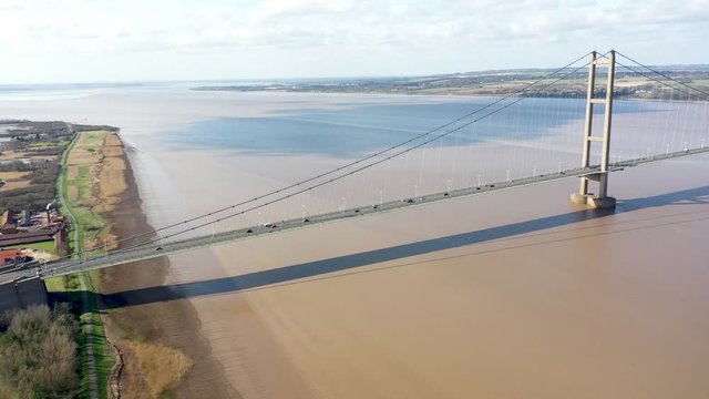 Aerial footage of The Humber Bridge, near Kingston upon Hull, East Riding of Yorkshire, England, single-span road suspension bridge, taken on a sunny day with a few white clouds in the sky.