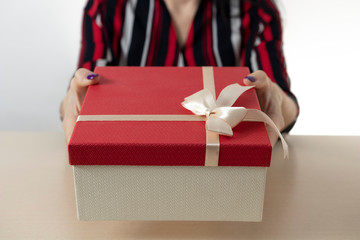 Female hands holding gift box. Copy space. Christmas, hew year, birthday concept. Festive background with bokeh and sunlight.