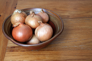 Bulb onions or common onions in a rustic pot
