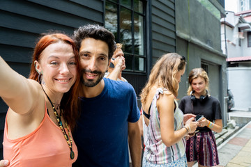 Two people making a selfie surrounded by more people with the mobile in the street