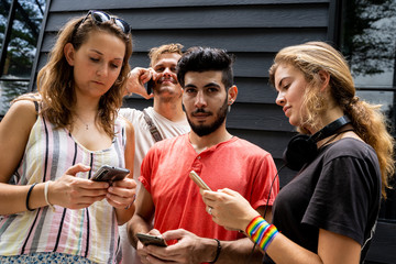 A group of young people from different ethnic groups looking at the mobile phone