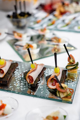 Variety of tasty delicious snacks. Close up of sliced meat on bread on a glass table. Delicious snack, appetizer on party or picnic time. Food concept