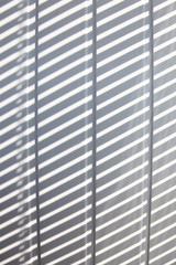 Vertical white plastic planks with gray diagonal sun rays shadows, texture for background