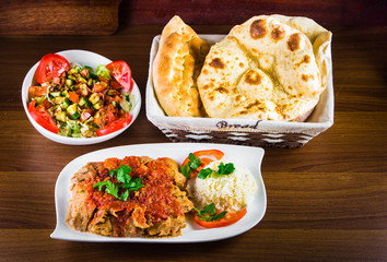 Traditional Turkish iskender kebap doner served with special red sauce and yogurt in the middle garnished with grilled tomatoes and peppers chicken