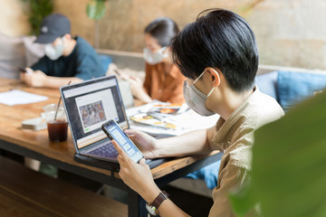 Asian people with protective masks prevent corona viruus working together at cafe.