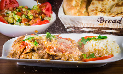 Traditional Turkish iskender kebap doner served with special red sauce and yogurt in the middle garnished with grilled tomatoes and peppers chicken