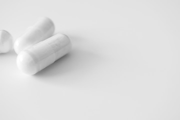 White medical pill capsules with selective focus on white background with copy space. Minimalist Healthcare and medicine science horizontal banner