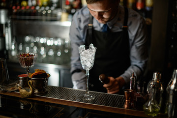 transparent glass with ice standing on bar counter.