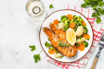 Grilled salmon fish steak with vegetables on white.