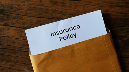 Insurance Policy Card In Envelope on wood background.