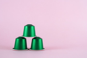 Close up of group of green replaceable capsules with coffee on pink background