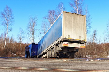 Wrecked semi truck on roadside ditch on sunny spring day, road accident