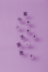 Scattered wooden letters in the form of the word Coronavirus purple