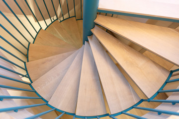 Spiral staircase, forged green handrail and wooden steps in modern home.
