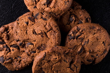 Appetizing chocolate chip cookies with slices of raisins on a black background.