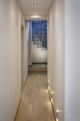 Spiral staircase, forged blue handrail and wooden steps in modern home. View from the corridor.
