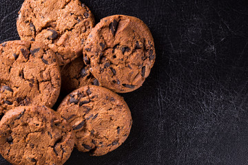 Appetizing chocolate chip cookies with slices of raisins on a black background.
