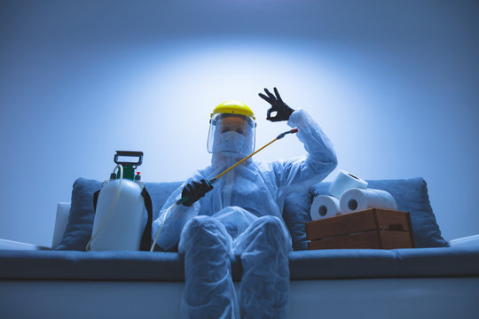 Scientist with protective suit and face mask, bio hazard sprayer for decontamination agaist viruses, germs - toilet paper stock paranoia at home, waiting for end of days.