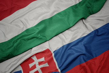 waving colorful flag of slovakia and national flag of hungary.
