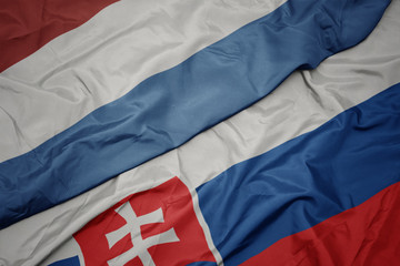 waving colorful flag of slovakia and national flag of luxembourg.