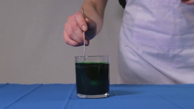 Putting chicken egg into Easter green dye